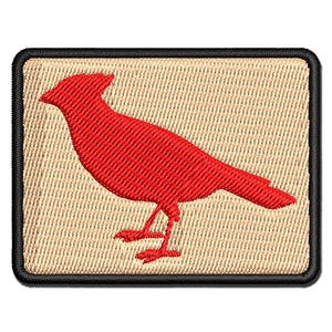 May include: A rectangular embroidered patch featuring a bright red cardinal bird silhouette centered on a light tan background, finished with a thick black stitched border around the entire perimeter of the rectangular shape.