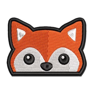 May include: An embroidered patch in the shape of a fox head. The design features bright orange fur, white accents on the ears and face, two large black circular eyes, and a small black nose, all outlined with a thick black stitched border.
