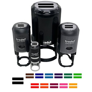May include: A collection of black Trodat self-inking stamps in various sizes, with the text "Trodat printy 46019", "Trodat printy 46020", and "Trodat printy 4612". The stamps have a double-line symbol on top. Below are color swatches of the double-line symbol.