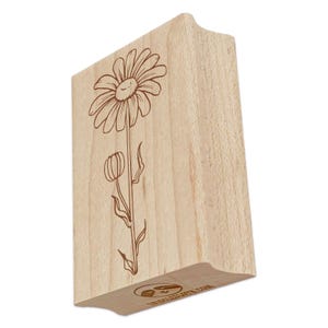 May include: A wooden stamp featuring a daisy design. The daisy is depicted with a smiling face and a stem with a bud. The stamp has a curved handle for easy use. The stamp is made of light-colored wood.