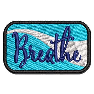 May include: A rectangular embroidered patch with rounded corners and a black border. The background features a bright turquoise field with a diagonal white wave pattern. The word Breathe is stitched in dark blue cursive script across the center.