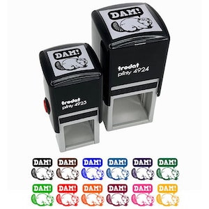 May include: Two black self-inking stamps with the word "DAM!" in a speech bubble and a beaver illustration. The stamps are labeled "trodat printy 4923" and "trodat printy 4924". Below are colorful stamp impressions.