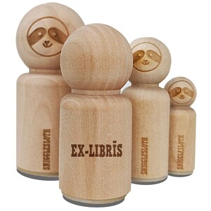 May include: A collection of wooden stamps featuring a sloth design. The central stamp reads "EX-LIBRIS" in a bold font. The stamps vary in size, with the sloth's face etched on the top. The text "SNIGGLESLOTH" is printed on the side of some stamps.