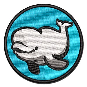 May include: A circular embroidered patch featuring a white beluga whale with black outlines against a bright cyan blue background. The patch is finished with a thick black stitched border that frames the entire circular design clearly.