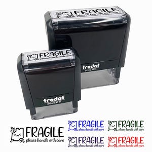 May include: Two black Trodat stamps with the text "FRAGILE please handle with care." The stamps are different sizes. Below the stamps are examples of the stamp in black, blue, green, and red.