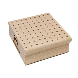 May include: A wooden stamp with a polka dot pattern. The stamp has a light brown color with evenly spaced brown dots. The stamp has a curved edge on one side and a logo on the side.
