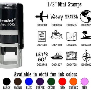 May include: A black and gray Trodat Printy 4612 stamp with travel-themed icons and text, including an airplane, globe, passport, and map. The image also shows eight ink color options: black, brown, blue, purple, green, red, orange, and pink.