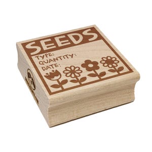 May include: A wooden stamp with the word "SEEDS" at the top. Below, it has spaces for "TYPE:" "QUANTITY:" and "DATE:" with flower illustrations. The stamp is light brown with dark brown text and illustrations.
