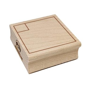 May include: A wooden stamp with a rectangular design and a smaller square in the upper left corner. The stamp has a light brown color and a visible wood grain. The side of the stamp has a logo and text.