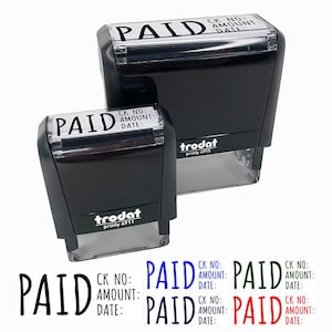 May include: Two black self-inking stamps with the word "PAID" in white lettering. The larger stamp has the text "CK NO: AMOUNT: DATE:" below the word "PAID". The smaller stamp has the same text but is smaller. Both stamps are made by Trodat.