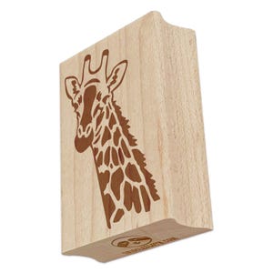 May include: A wooden stamp featuring a giraffe's head and neck with a brown, patterned design. The stamp has a curved handle and a logo at the bottom. The giraffe's head is angled to the left.