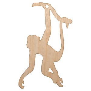 May include: A wooden cutout of a monkey hanging from a branch. The monkey is light brown with a smooth finish and a hole at the top for hanging. The monkey is hanging upside down, with its arms and legs extended.