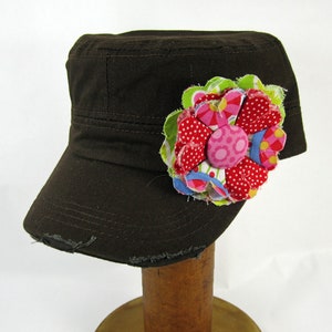 May include: A brown canvas baseball cap with a fabric flower embellishment. The flower is made of pink, red, green, blue, and white fabric.