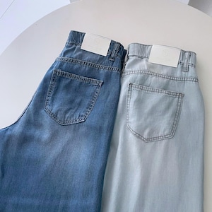 Puede incluir: Dos pares de pantalones vaqueros en tonos azul medio y azul claro. Cada par cuenta con una cintura el&aacute;stica, trabillas para cintur&oacute;n, un bolsillo trasero y una etiqueta de marca rectangular blanca cosida en la parte posterior.
