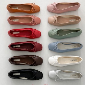 May include: Twelve ballet flats arranged in two columns, featuring a square toe and a small decorative bow on the front. The shoes come in various colors including tan, pink, red, burgundy, brown, black, beige, sage green, blue, white, and silver.
