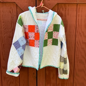 May include: A white quilted jacket with a hood. The jacket is made of patchwork fabric in various colors, including red, green, blue, and pink.