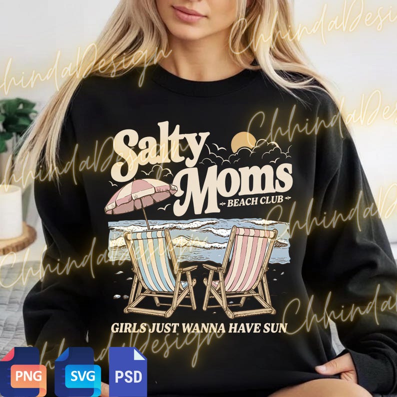 May include: Black sweatshirt featuring a beach scene graphic. The design includes the text "Salty Moms Beach Club" with illustrations of beach chairs, an umbrella, and ocean waves. The phrase "Girls Just Wanna Have Sun" is also included.