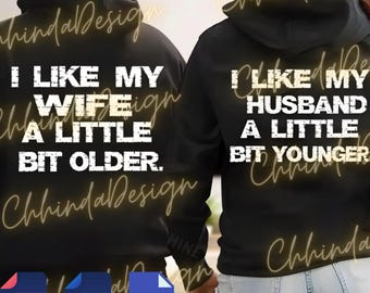 Könnte beinhalten: Schwarze Kapuzenpullover mit weißem Text: "I LIKE MY WIFE A LITTLE BIT OLDER" und "I LIKE MY HUSBAND A LITTLE BIT YOUNGER". Die Kapuzenpullover haben eine Kapuze und sind ein passendes Set.