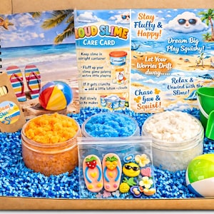 Pode incluir: Um kit de slime com tema de praia em uma caixa de papelão, preenchido com papel azul picado. O kit inclui potes de slime laranja, azul e branco, uma bola de praia, um balde e uma pá verdes e um bloco de notas.