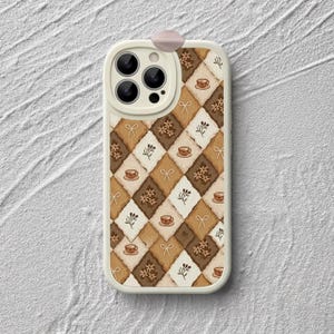 May include: A phone case featuring a repeating diamond pattern in shades of brown, tan, and cream. The design includes small illustrations of teacups, floral clusters, and simple bows distributed across the alternating colored diamond shapes.