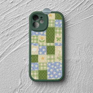 May include: A green phone case with a patchwork design featuring a variety of colours, including blue, green, yellow, and white. The case has a cutout for the camera lens and a small hole for the microphone.