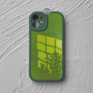 May include: A green phone case with a painted design of a window and plant shadows. The case has a dark green border and camera cutout. The background is a textured white surface.