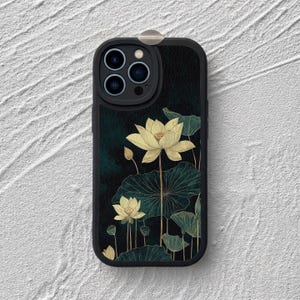 May include: A black smartphone case featuring a dark teal background with a printed design of pale yellow lotus flowers and large, detailed green lily pads. The case has a raised camera cutout section and a small metallic tab at the top edge.