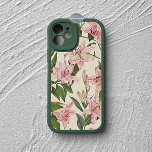May include: A green phone case with a floral design featuring pink lilies on a cream background.