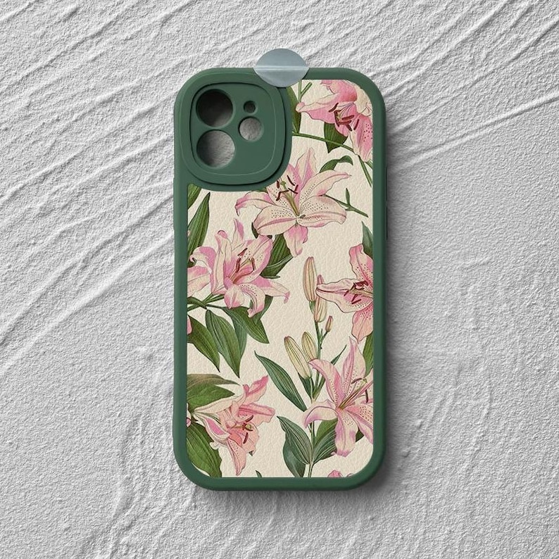 May include: A green phone case with a floral design featuring pink lilies on a cream background.