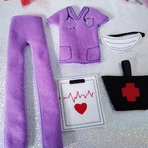 May include: A set of purple felt medical scrubs, a face mask, and a black bag with a red cross. Also included is a white notepad with a red heart and a red heartbeat line. The scrubs have a stethoscope design.