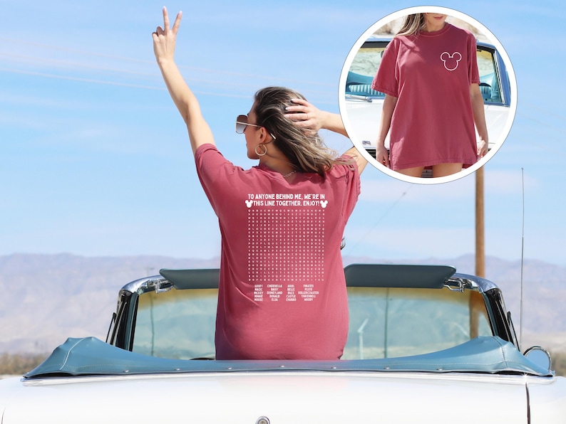 May include: A maroon t-shirt featuring a white Mickey Mouse head on the front and text on the back. The back of the shirt has the text "TO ANYONE BEHIND ME, WE'RE IN THIS LINE TOGETHER. ENJOY!" with a grid of dots and more text.