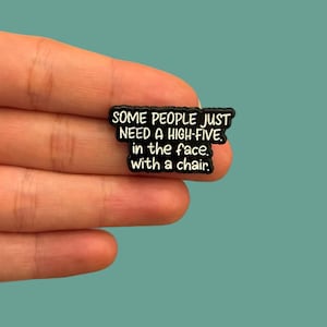 May include: A black rectangular pin with white text that reads "SOME PEOPLE JUST NEED A HIGH-FIVE. in the face. with a chair."