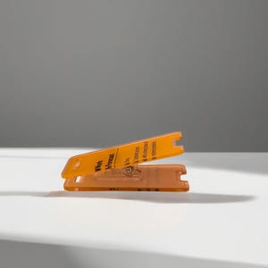 May include: Orange plastic card with the text "Work in Progress" and a small metal screw. The card is folded in half.