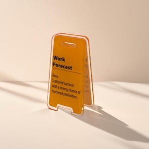 May include: A yellow and orange plastic sign with the text "Work Forecast" and the description "Busy. Scattered sarcasm with a strong chance of muttered profanities."