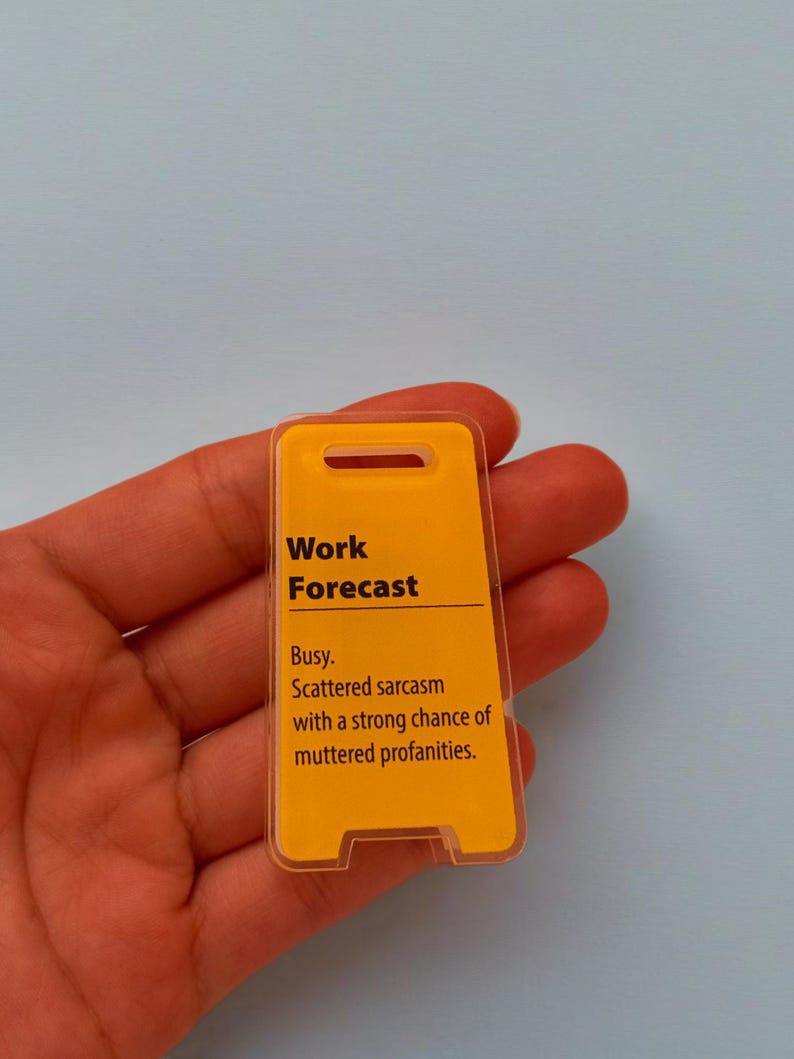 May include: A yellow and clear plastic sign with the text "Work Forecast" and the description "Busy. Scattered sarcasm with a strong chance of muttered profanities."