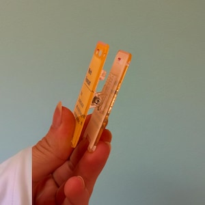 May include: A yellow plastic clip with a clear window and the text "Week Forecast" printed on it.