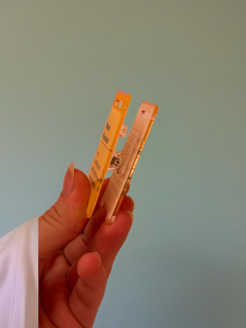 May include: A yellow plastic clip with a clear window and the text "Week Forecast" printed on it.
