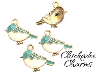 May include: Three gold-tone metal bird charms with blue and white enamel paint. The birds are in a sitting position with their wings out. The charms are labeled "Chickadee Charms".