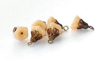 May include: Five cream-colored glass beads with ornate gold metal caps. The beads have a flower-like shape and are strung on a wire.