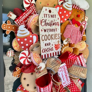 Puede incluir: Una corona navide&ntilde;a festiva con hombres de jengibre, galletas, caramelos de menta y cintas rojas y blancas con lunares. La corona incluye un letrero que dice "It's Not Christmas Without Cookies and Cocoa."