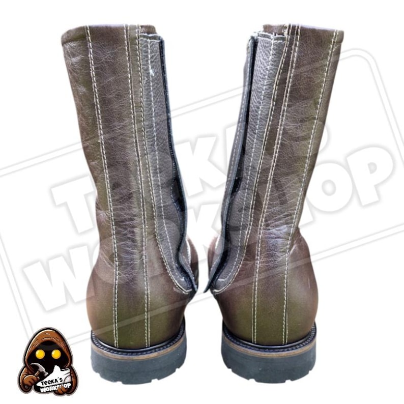 May include: A pair of brown leather boots with white stitching and a zipper closure. The boots have a rugged, workwear style with a dark sole and a mid-calf height.