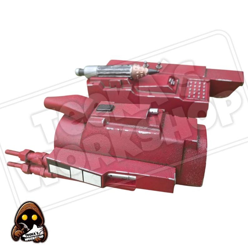 May include: A red prop weapon with a cylindrical body and various protruding details. The prop has a textured surface and appears to be made of a durable material. It features a silver and copper-colored component on top and rectangular white accents.
