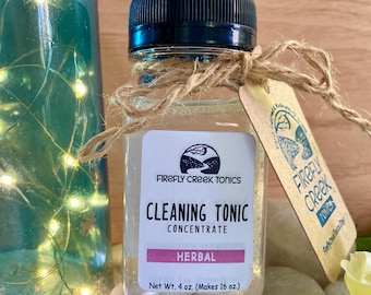 May include: A clear glass bottle with a black lid and a brown twine bow. The bottle contains a clear liquid and has a white label that reads "Firefly Creek Tonics Cleaning Tonic Concentrate Herbal Net Wt. 4 oz. (Makes 16 oz.)".