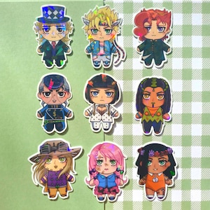May include: Nine colorful stickers featuring anime-style characters with large eyes and various outfits. The stickers have a holographic effect and are arranged on a green and white checkered background. Each character has a unique hairstyle and expression.