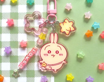 May include: A pink keychain with a cartoon bunny charm, star-shaped charm, and a charm that says "USAGI". The keychain has a pink clasp and is surrounded by colorful star-shaped beads.