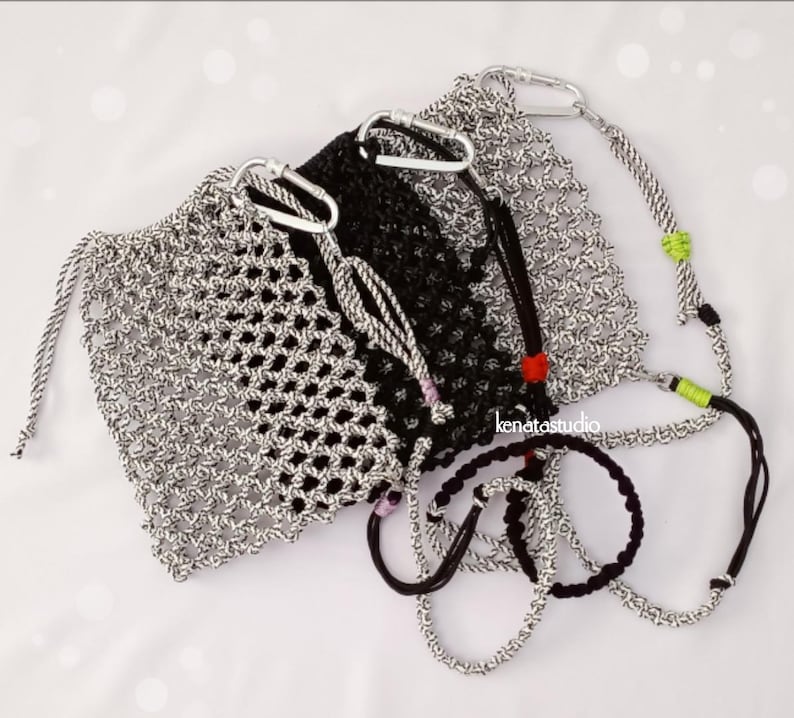 May include: A collection of handmade macrame bags and bracelets in black and silver. The bags feature a drawstring closure and carabiner clips. The bracelets are black and silver, with a variety of cord designs. The bags and bracelets are displayed on a white surface.