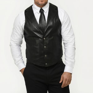 May include: A black leather waistcoat with a notched lapel, worn over a white dress shirt and black tie. The waistcoat has a button-down closure and a tailored fit. The outfit is completed with black trousers.