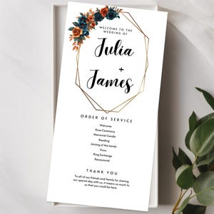 May include: A wedding program with the names "Julia + James" in elegant script, framed by a gold geometric design. The top left corner features a floral arrangement in shades of blue, orange, and rust. The program lists the order of service and a thank you message.