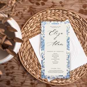Może przedstawiać: Program ślubu z niebieskimi kwiatowymi akcentami i imionami "Eliza & Adam" w eleganckiej czcionce. Program zawiera porządek ceremonii i podziękowania, na kremowym tle.
