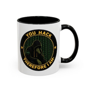 May include: A white ceramic mug with a black handle and interior rim. The front features a circular graphic of a hooded figure in a binary code background with the yellow text YOU HACK THEREFORE I AM surrounding the central image.